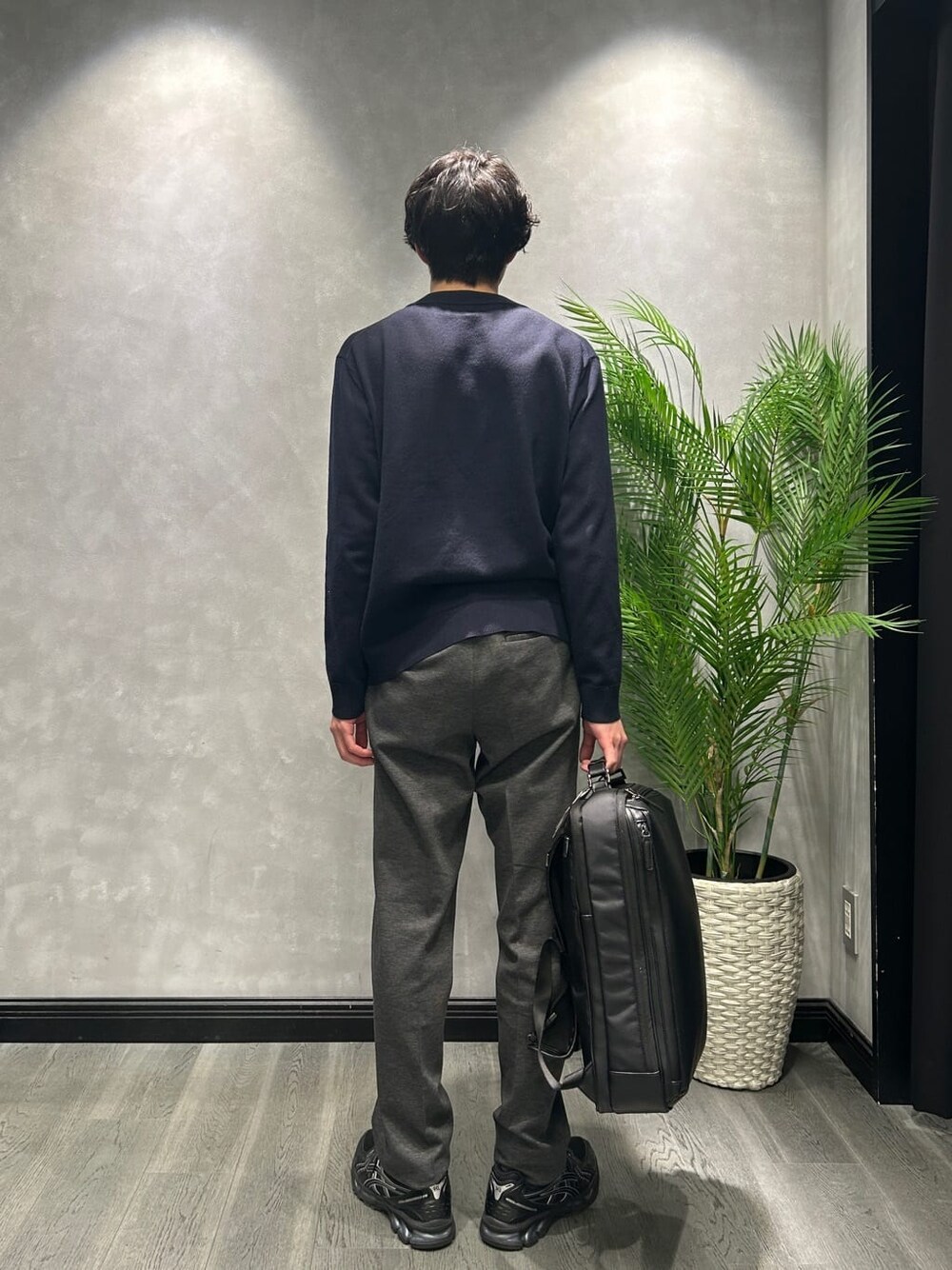 ブルー系のニット/セーター、ブラック系のスラックス、ブラック系のバックパック/リュックを着用したメンズの冬コーディネートの3枚目の写真