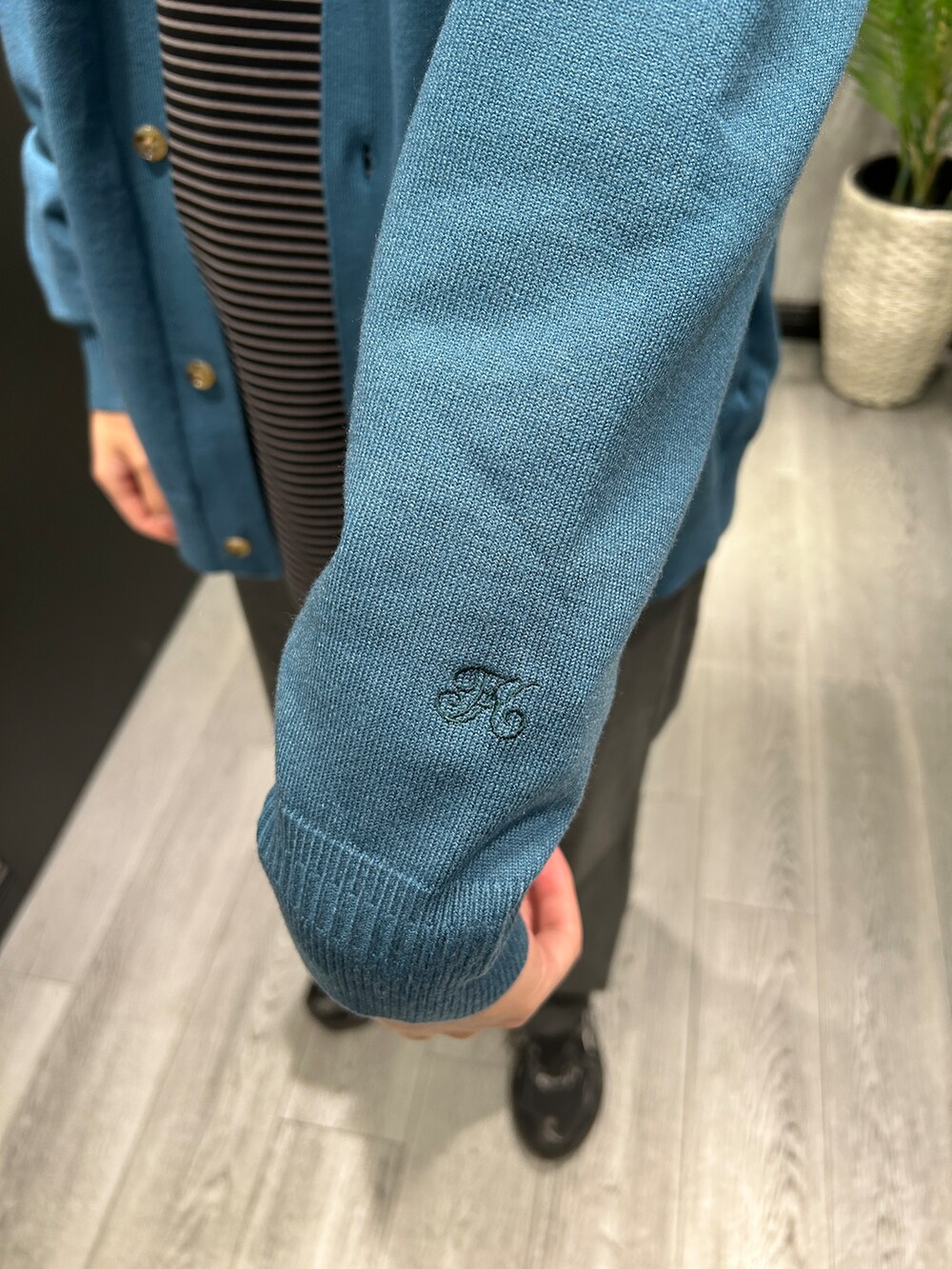 ブルー系のニット/セーター、ブラック系のTシャツ/カットソー、グレー系のスラックスを着用したメンズの秋コーディネートの5枚目の写真