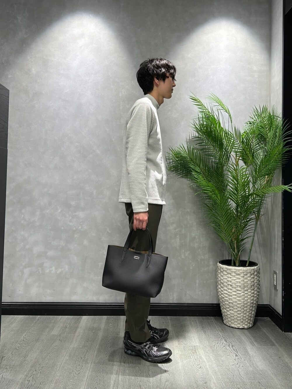 グレー系のTシャツ/カットソー、グリーン系のスラックス、ブラック系のトートバッグを着用したメンズの冬コーディネートの2枚目の写真