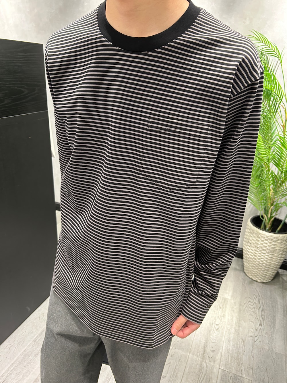 ブラック系のTシャツ/カットソー、グレー系のスラックス、ブルー系のトートバッグを着用したメンズの秋コーディネートの4枚目の写真