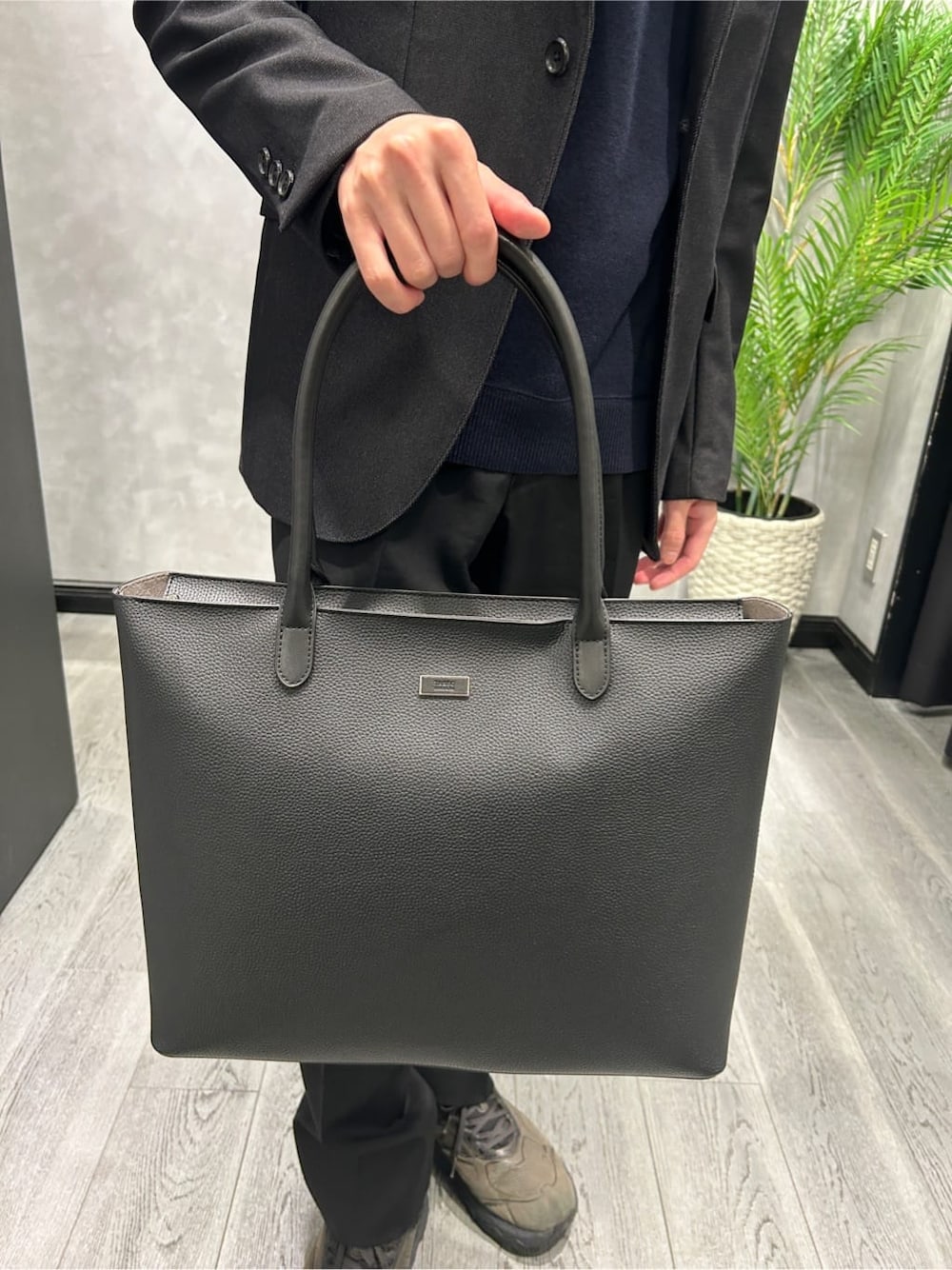 ベージュ系のダウンジャケット/コート、ブルー系のニット/セーター、ブラック系のトートバッグを着用したメンズの秋コーディネートの9枚目の写真