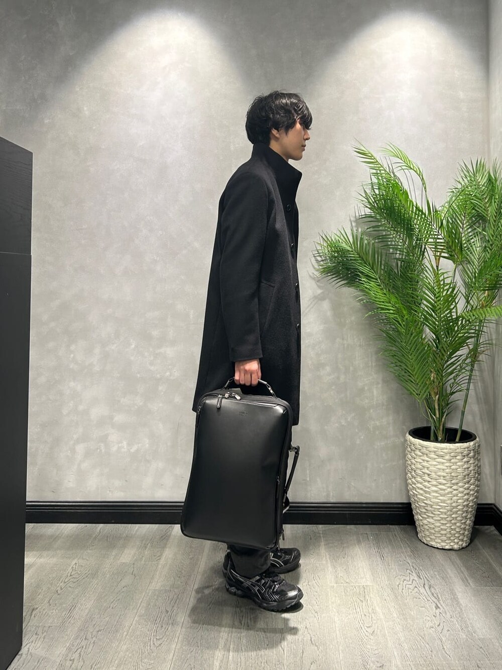 ブラック系のその他アウター、ブルー系のニット/セーター、ブラック系のスラックスを着用したメンズの冬コーディネートの2枚目の写真