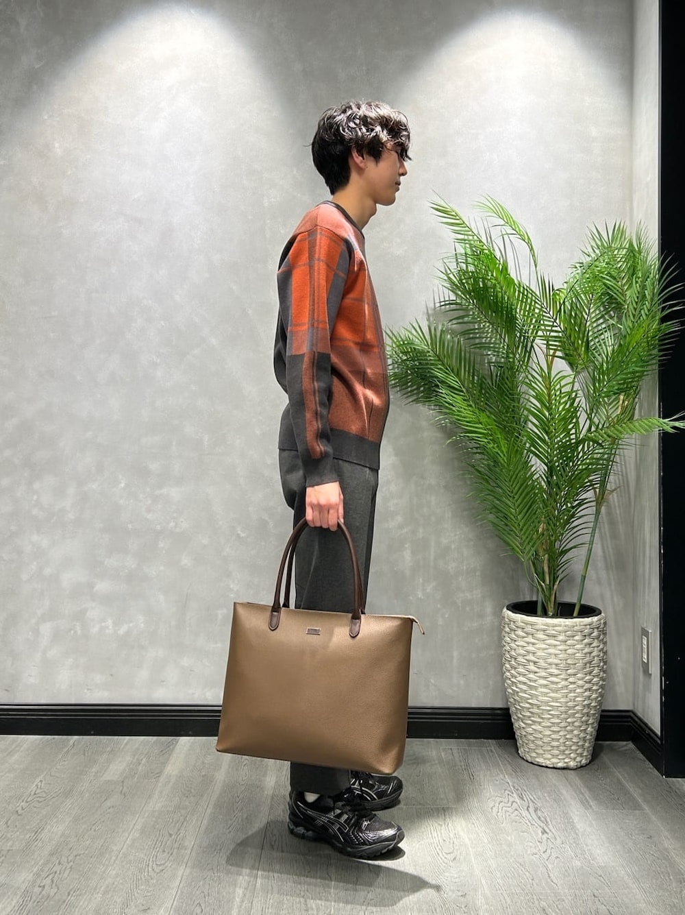 グレー系のニット/セーター、ブラック系のスラックス、ブラウン系のトートバッグを着用したメンズの冬コーディネートの2枚目の写真