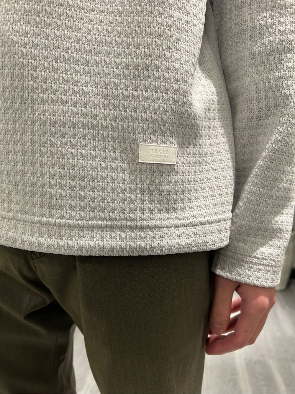 グレー系のTシャツ/カットソー、グリーン系のスラックス、ブラック系のトートバッグを着用したメンズの冬コーディネートの5枚目の写真