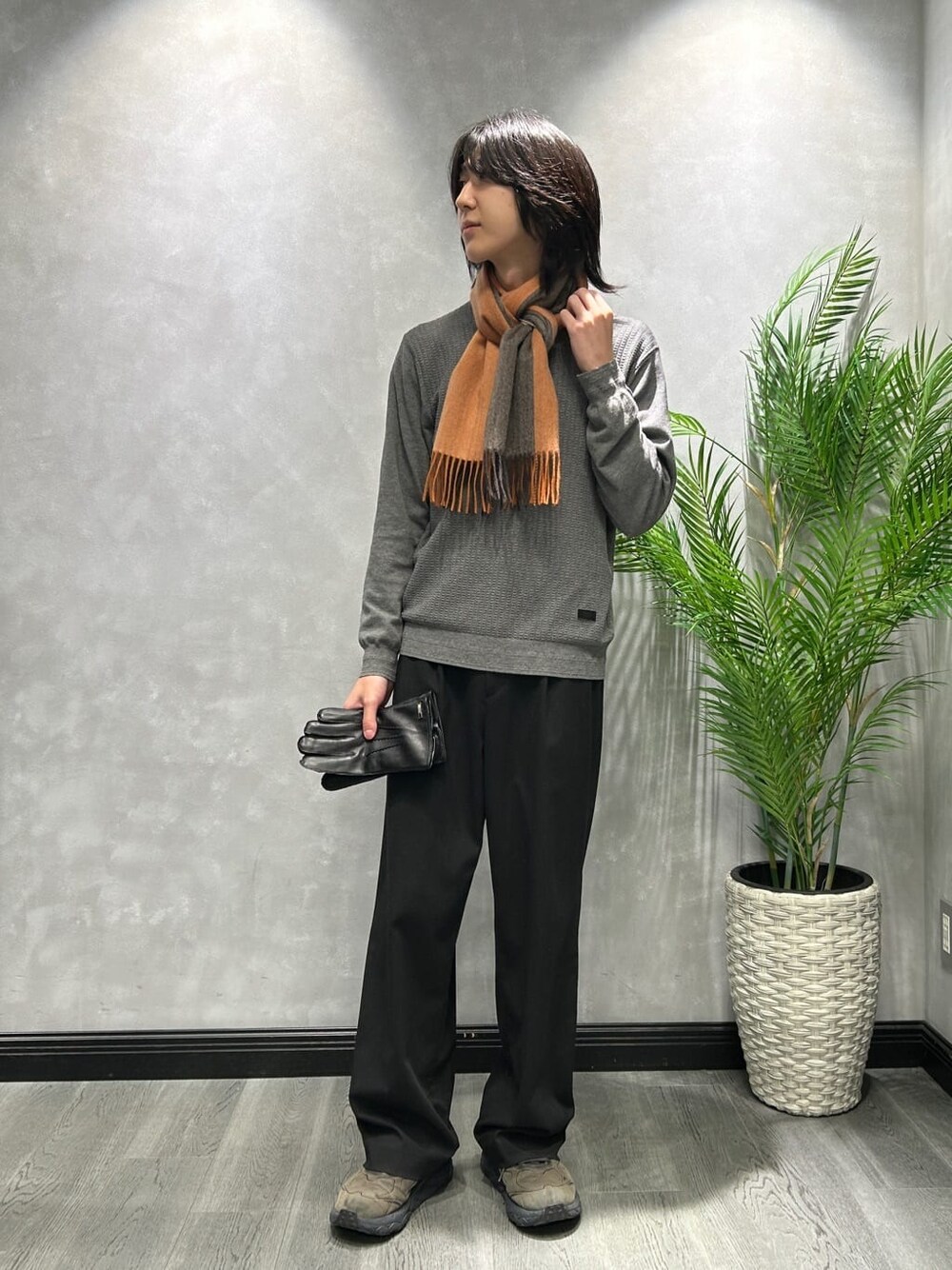 ブラウン系のその他アウター、グレー系のニット/セーター、オレンジ系のマフラーを着用したメンズの秋コーディネートの7枚目の写真