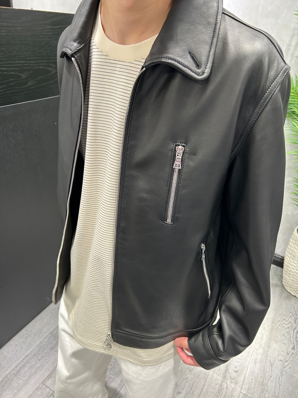 ブラック系のブルゾン、ホワイト系のTシャツ/カットソー、ホワイト系のデニムパンツを着用したメンズの秋コーディネートの4枚目の写真
