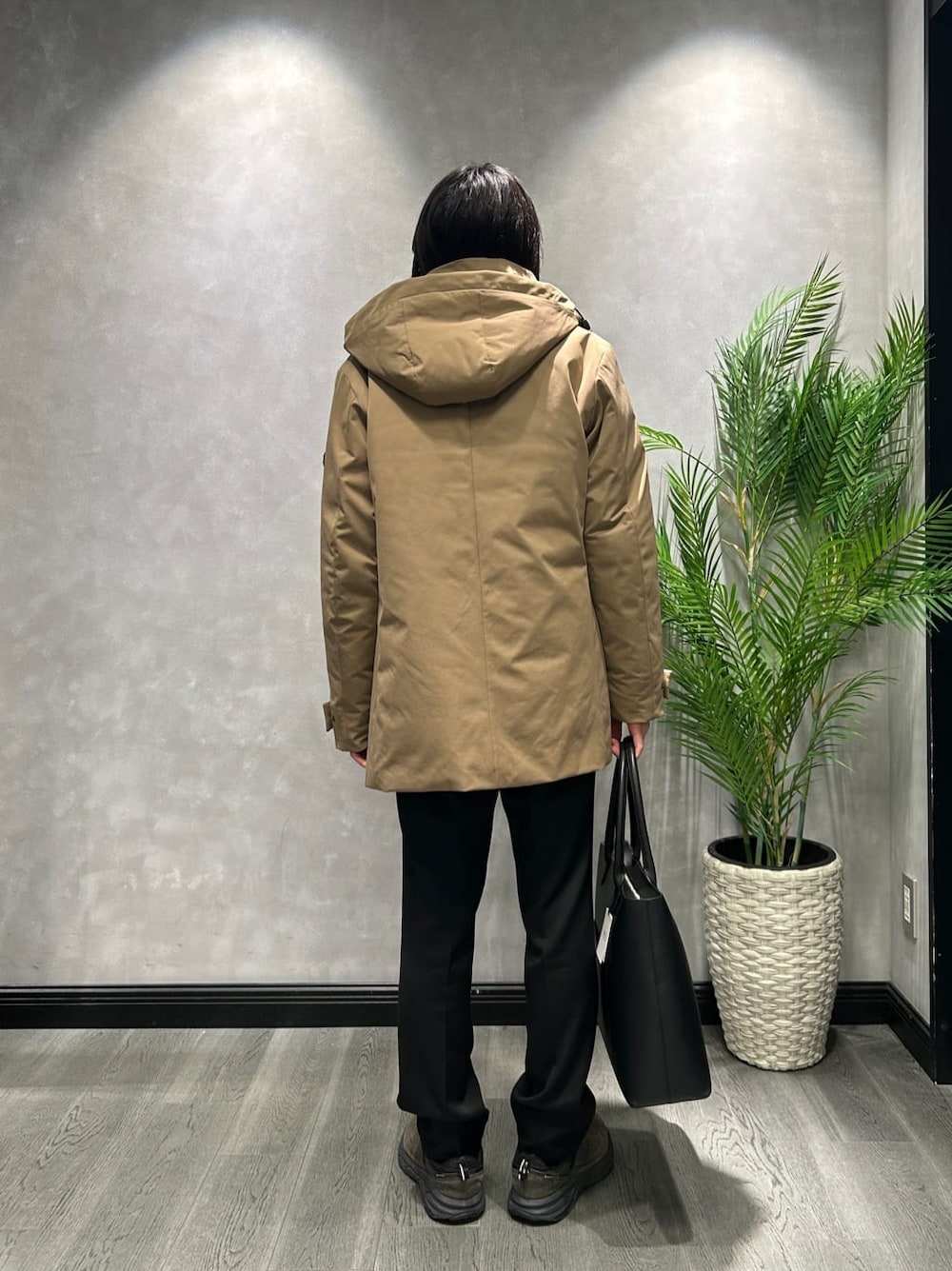 ベージュ系のダウンジャケット/コート、ブルー系のニット/セーター、ブラック系のトートバッグを着用したメンズの秋コーディネートの3枚目の写真