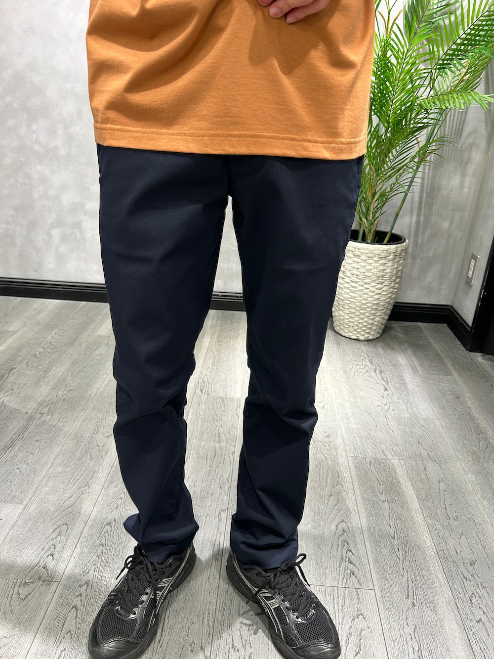 オレンジ系のTシャツ/カットソー、ブルー系のスラックス、ブルー系のトートバッグを着用したメンズの夏コーディネートの6枚目の写真