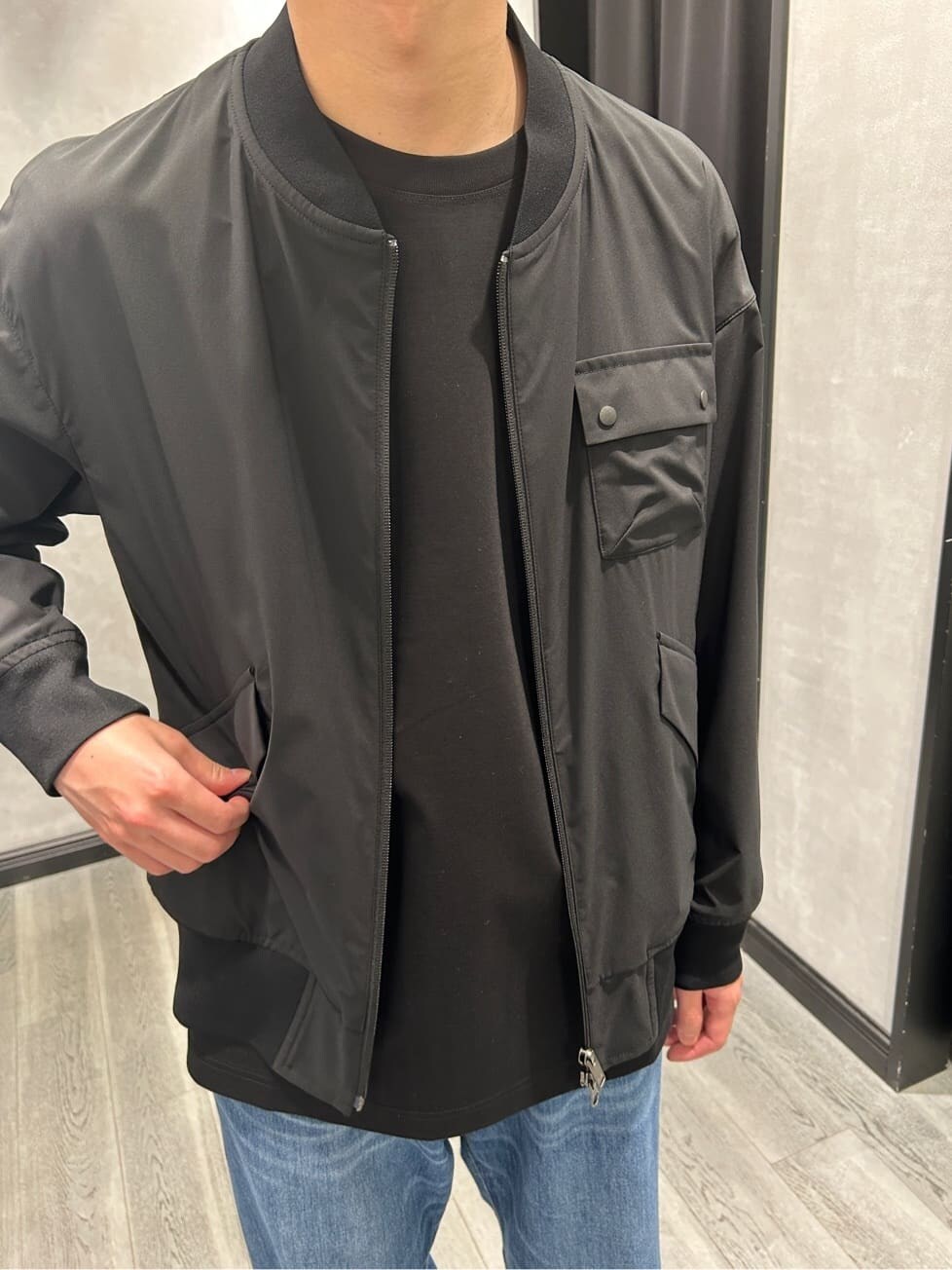 ブラック系のブルゾン、ブラック系のTシャツ/カットソー、ブルー系のデニムパンツを着用したメンズの春コーディネートの4枚目の写真