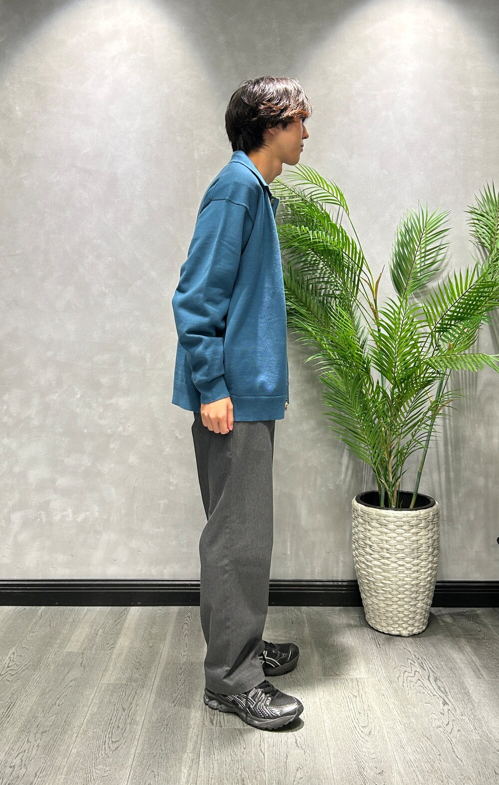 ブルー系のニット/セーター、ブラック系のTシャツ/カットソー、グレー系のスラックスを着用したメンズの秋コーディネートの2枚目の写真