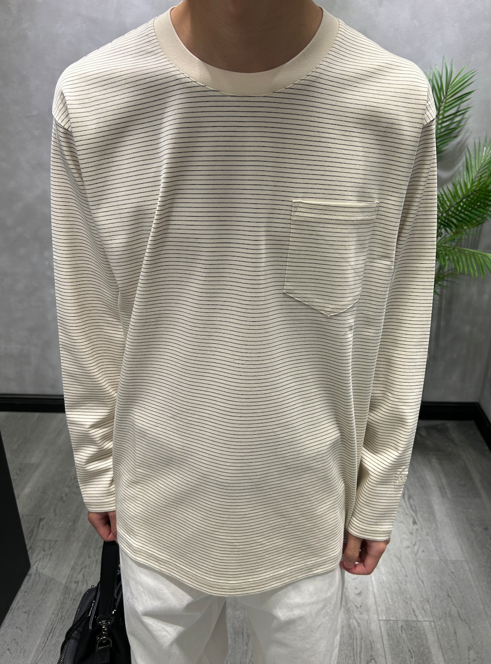 ブラック系のブルゾン、ホワイト系のTシャツ/カットソー、ホワイト系のデニムパンツを着用したメンズの秋コーディネートの5枚目の写真