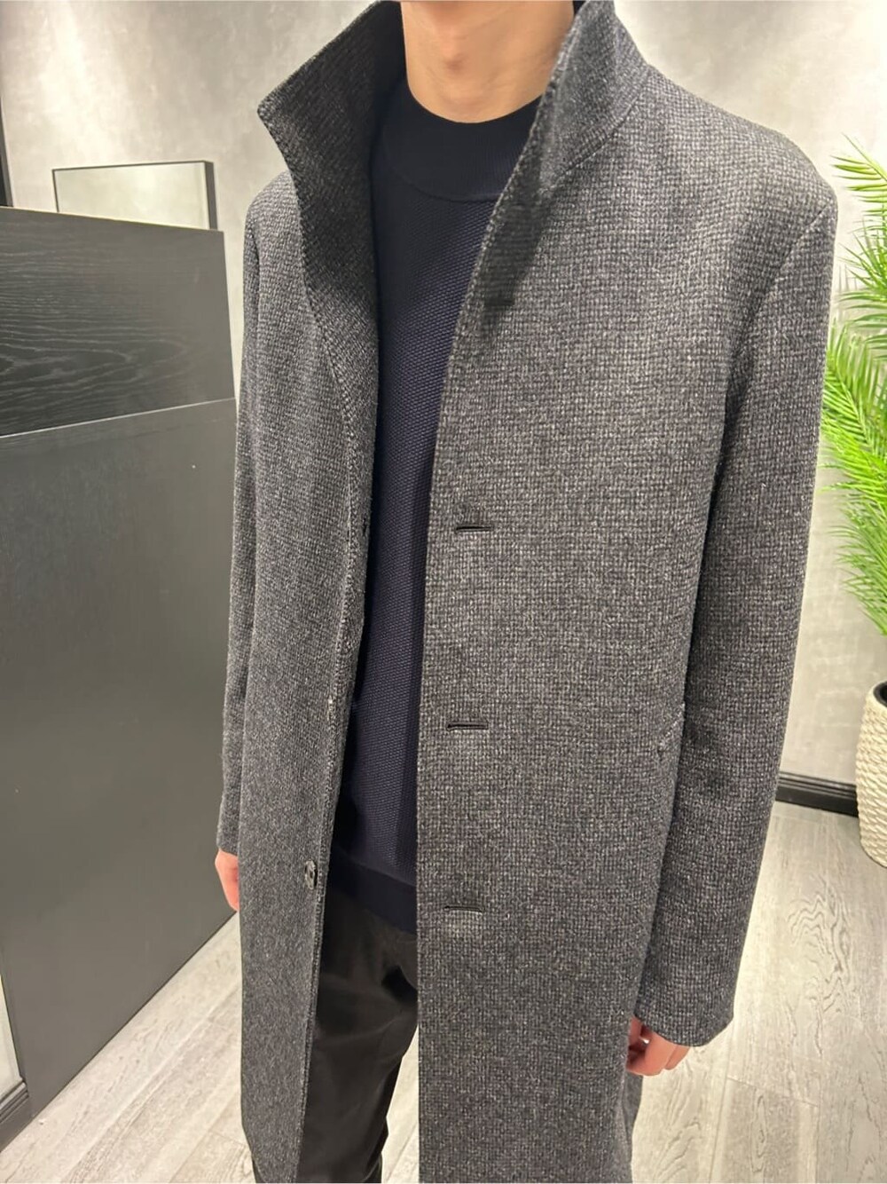 グレー系のその他アウター、ブラック系のスラックス、ブルー系のニット/セーターを着用したメンズの冬コーディネートの4枚目の写真
