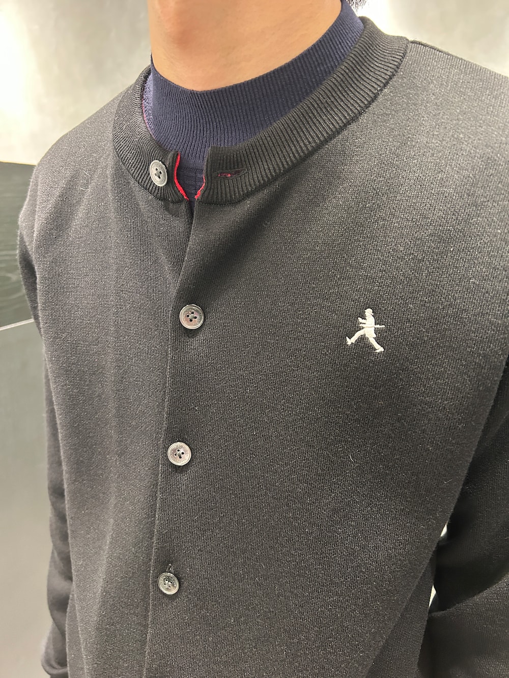 ブラック系のカーディガン/ボレロ、ブルー系のニット/セーター、グリーン系のスラックスを着用したメンズの秋コーディネートの5枚目の写真