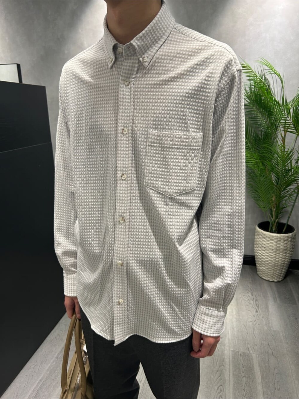 グレー系のシャツ/ブラウス、ブラック系のスラックス、ベージュ系のトートバッグを着用したメンズの冬コーディネートの7枚目の写真