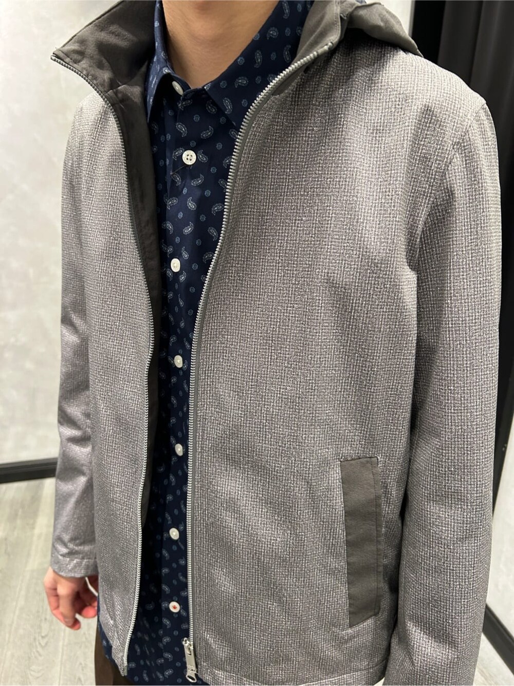 グレー系のブルゾン、ブルー系のシャツ/ブラウス、ブラウン系のスラックスを着用したメンズの春コーディネートの4枚目の写真