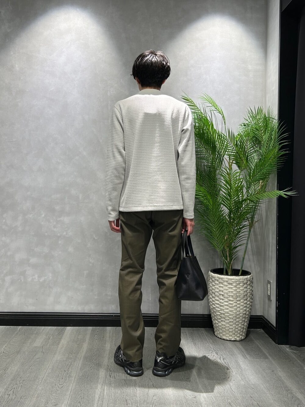 グレー系のTシャツ/カットソー、グリーン系のスラックス、ブラック系のトートバッグを着用したメンズの冬コーディネートの3枚目の写真