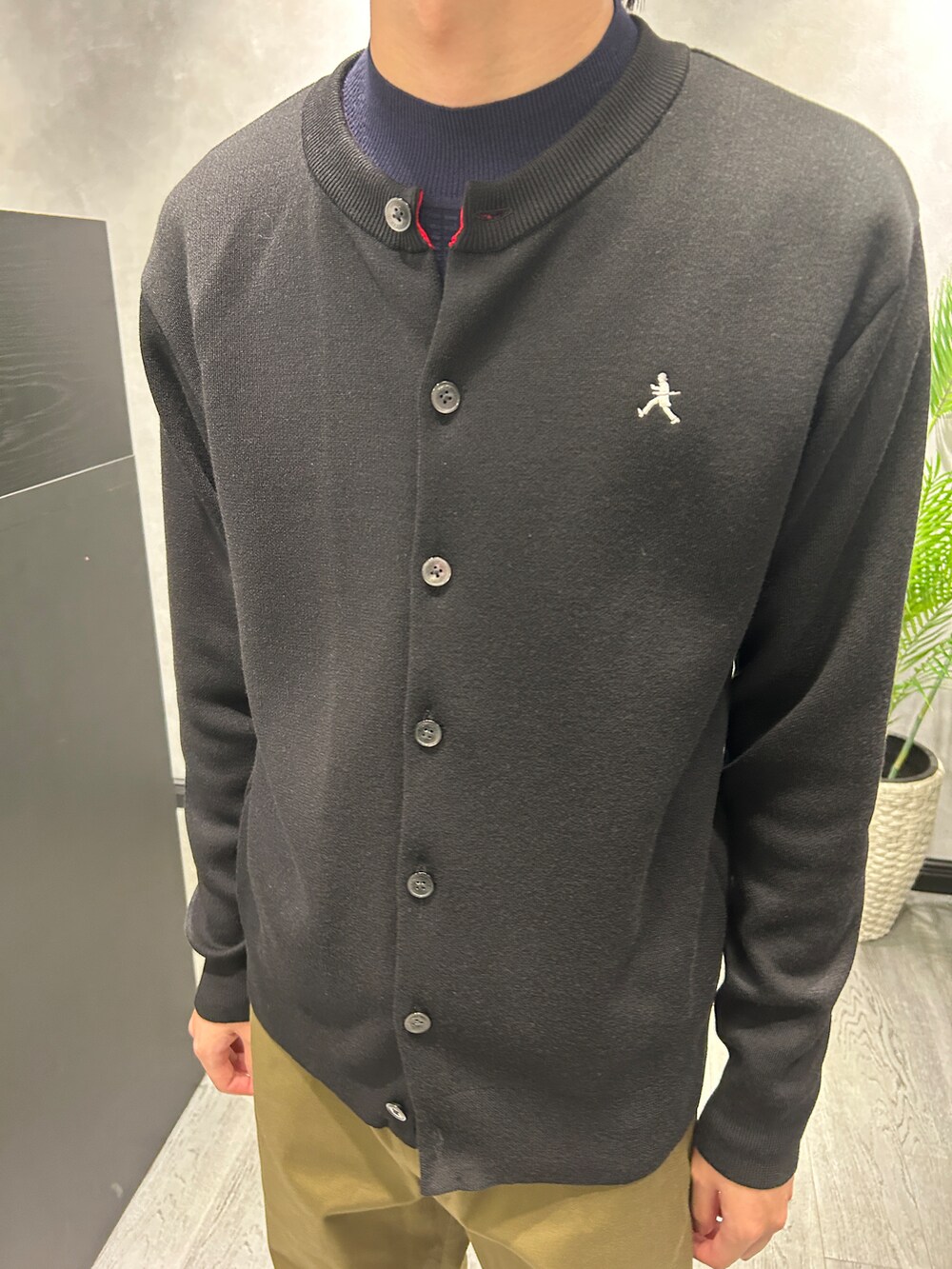 ブラック系のカーディガン/ボレロ、ブルー系のニット/セーター、グリーン系のスラックスを着用したメンズの秋コーディネートの4枚目の写真