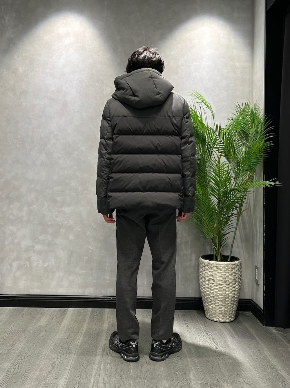 ブラック系のダウンジャケット/コート、グレー系のニット/セーター、ブラック系のスラックスを着用したメンズの冬コーディネートの3枚目の写真