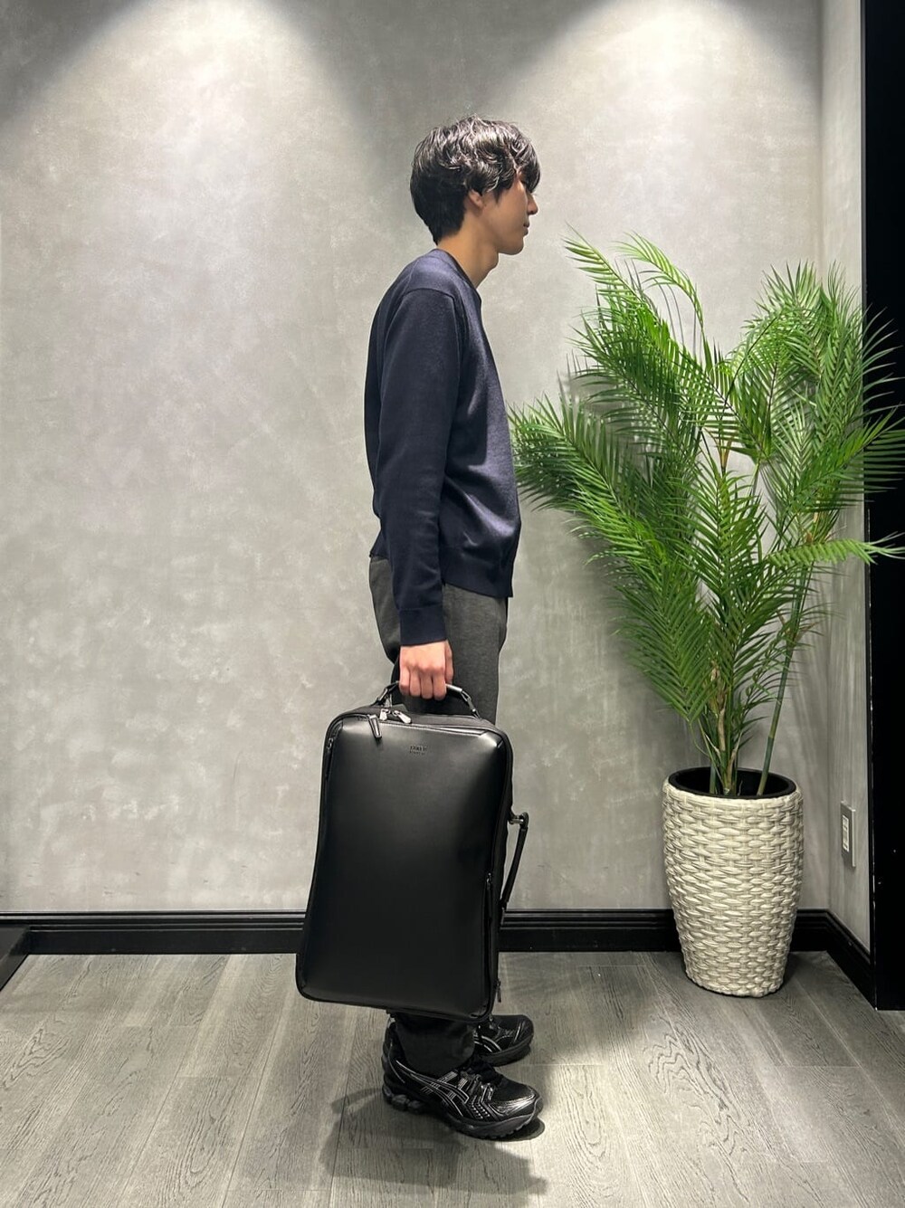 ブルー系のニット/セーター、ブラック系のスラックス、ブラック系のバックパック/リュックを着用したメンズの冬コーディネートの2枚目の写真