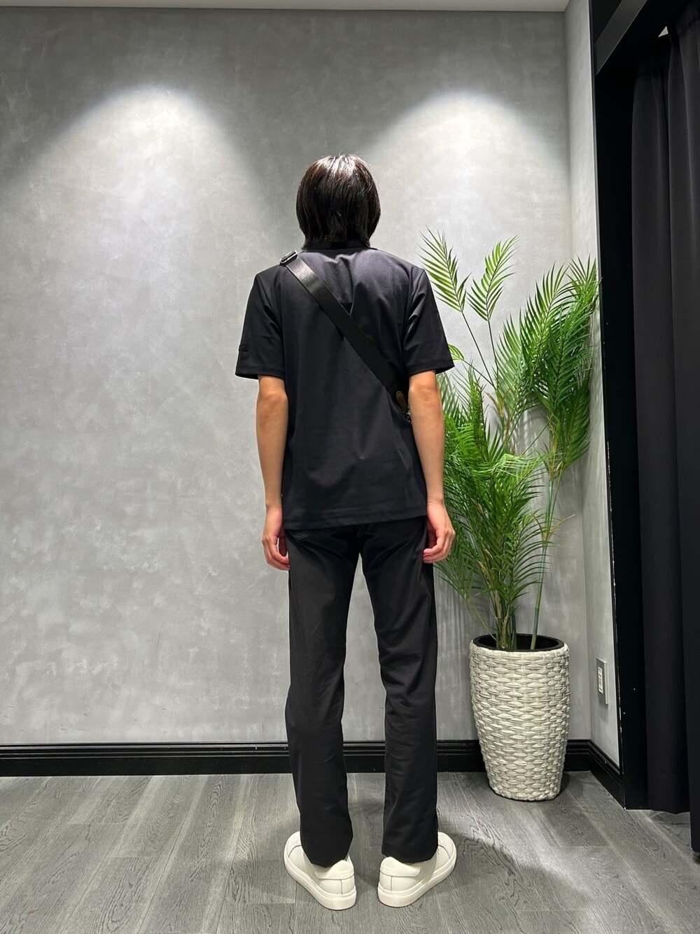 ブラック系のスラックス、ブラウン系のボディバッグ/ウエストポーチ、ホワイト系のスニーカーを着用したメンズの秋コーディネートの3枚目の写真