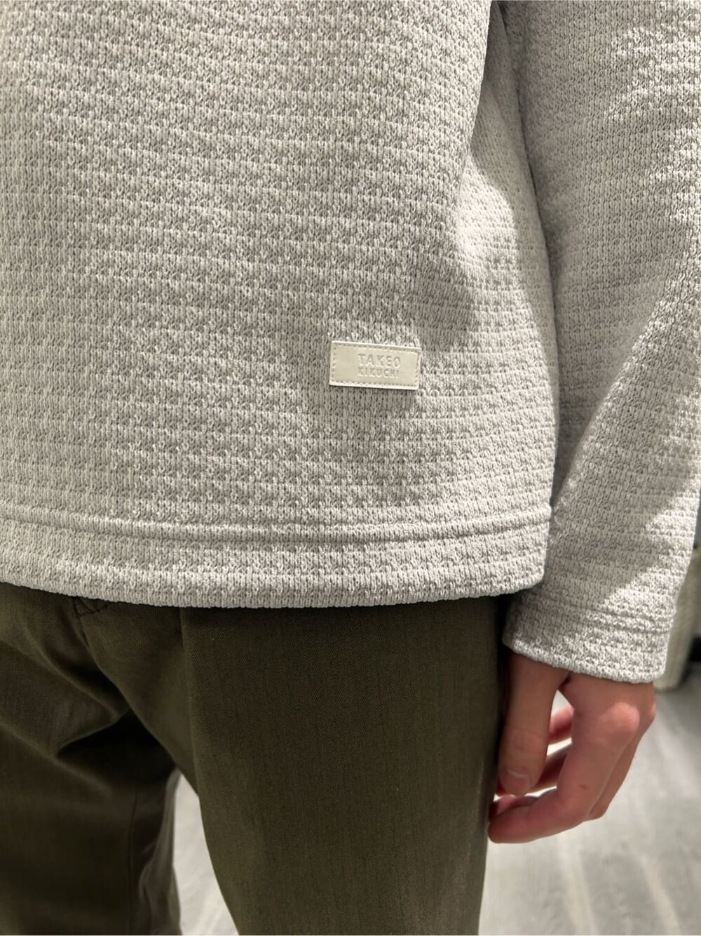 ブラウン系のステンカラーコート、グレー系のTシャツ/カットソー、グリーン系のスラックスを着用したメンズの冬コーディネートの8枚目の写真