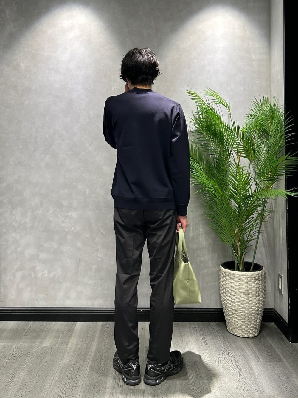 ブルー系のニット/セーター、ブラック系のスラックス、グリーン系のトートバッグを着用したメンズの冬コーディネートの3枚目の写真