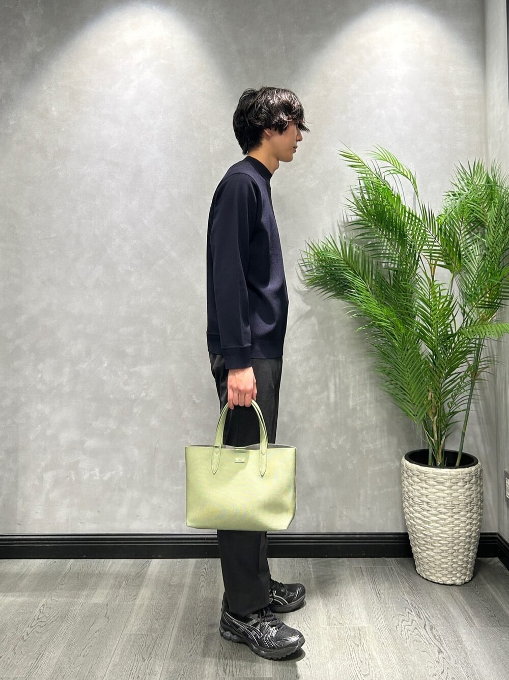 ブルー系のニット/セーター、ブラック系のスラックス、グリーン系のトートバッグを着用したメンズの冬コーディネートの2枚目の写真