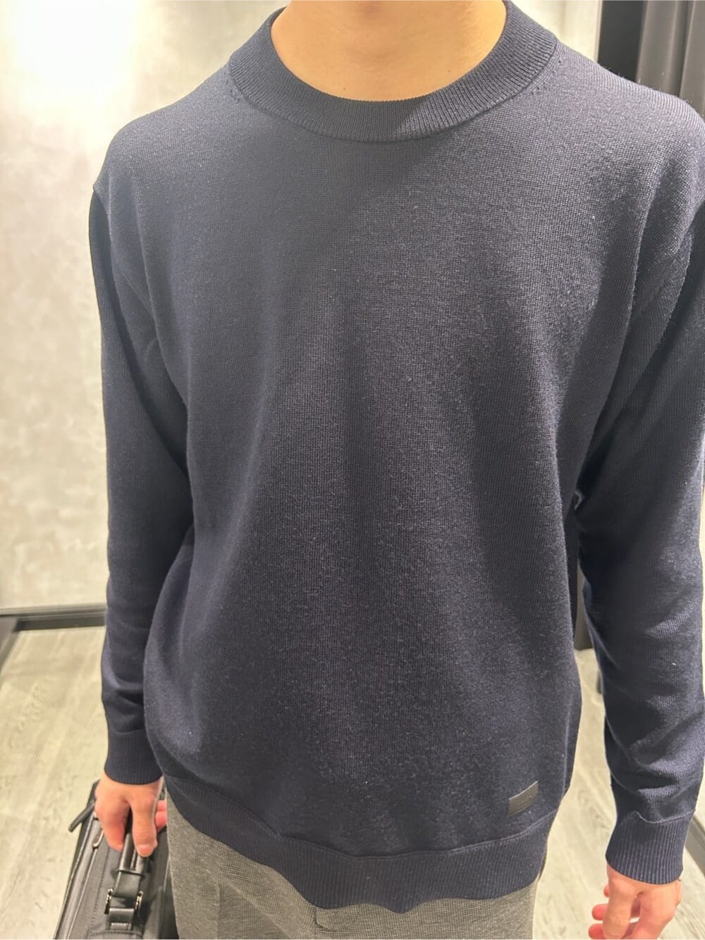 ブルー系のニット/セーター、ブラック系のスラックス、ブラック系のバックパック/リュックを着用したメンズの冬コーディネートの5枚目の写真