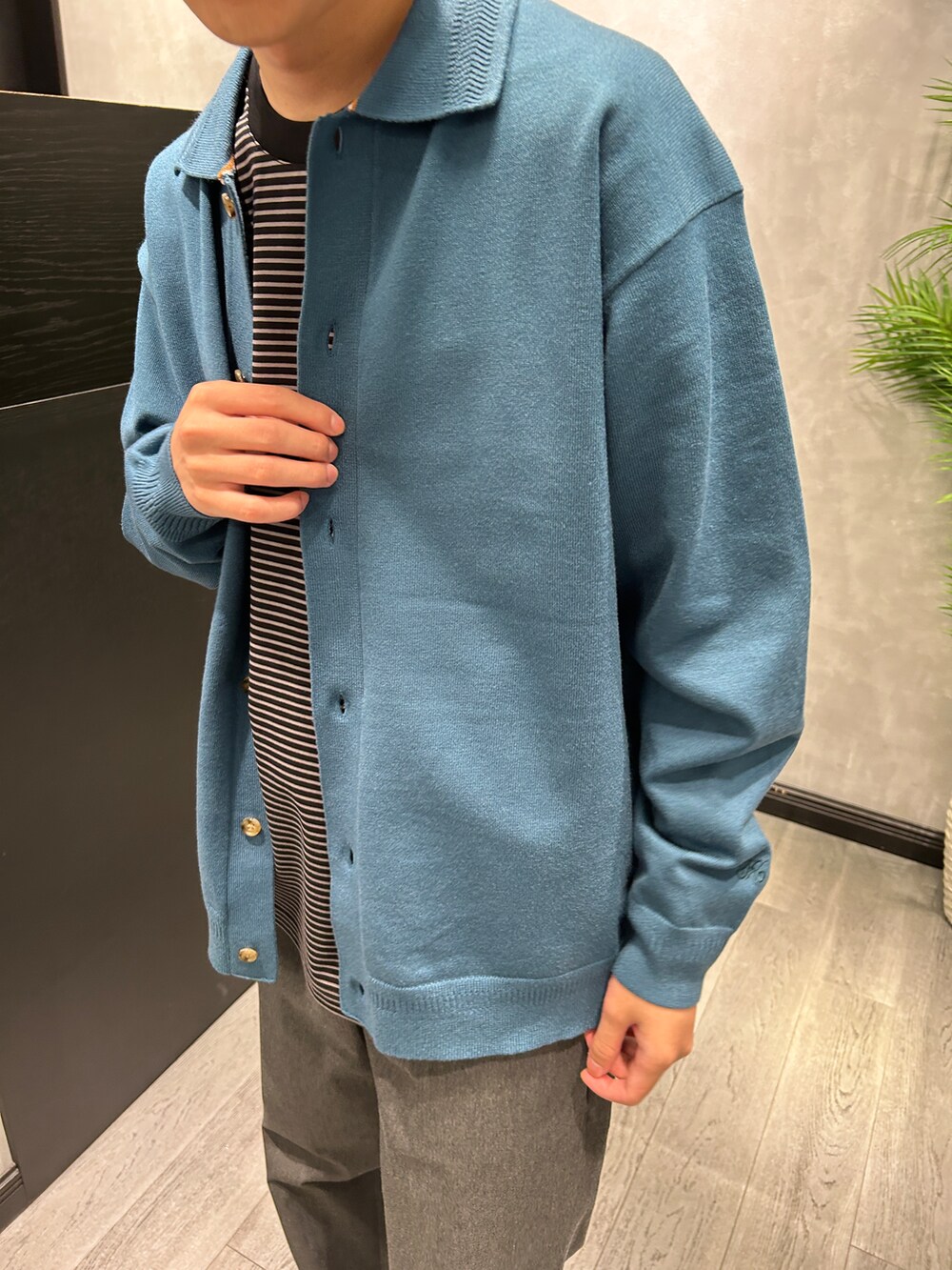 ブルー系のニット/セーター、ブラック系のTシャツ/カットソー、グレー系のスラックスを着用したメンズの秋コーディネートの4枚目の写真
