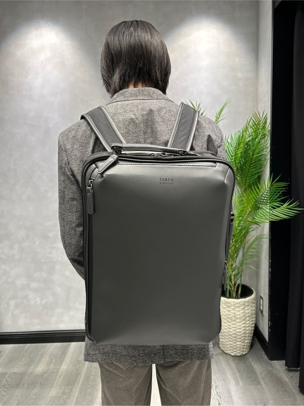 ブラック系のテーラードジャケット、ブラック系のスラックス、グレー系のバックパック/リュックを着用したメンズの夏コーディネートの6枚目の写真