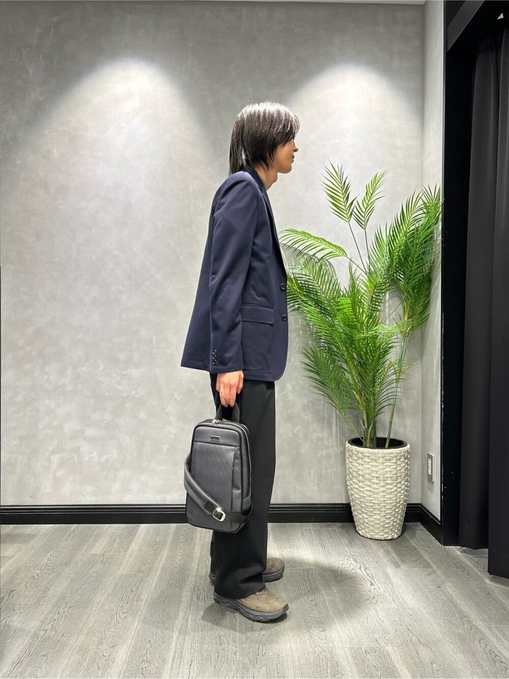グレー系のニット/セーター、ブルー系のテーラードジャケット、グレー系のショルダーバッグを着用したメンズの秋コーディネートの2枚目の写真
