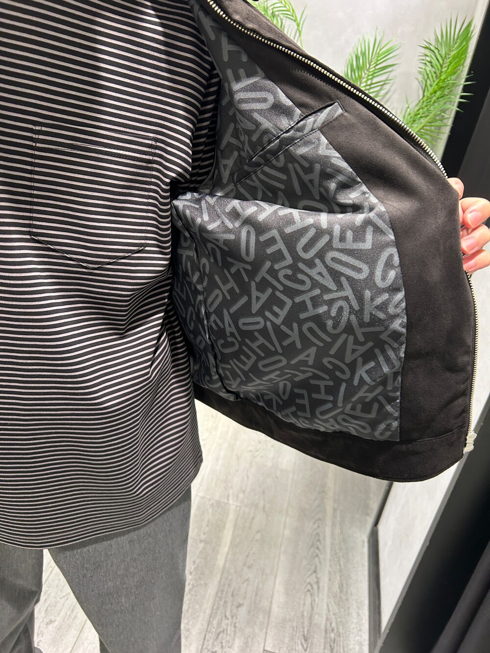 ブラック系のブルゾン、ブラック系のTシャツ/カットソー、グレー系のスラックスを着用したメンズの秋コーディネートの5枚目の写真