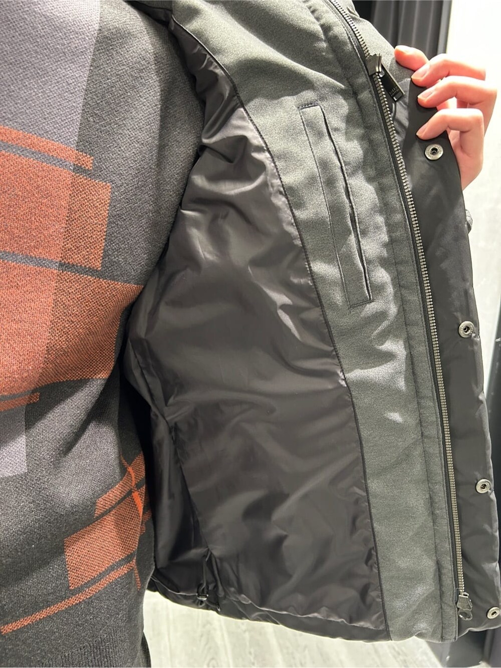 ブラック系のダウンジャケット/コート、グレー系のニット/セーター、ブラック系のスラックスを着用したメンズの冬コーディネートの5枚目の写真