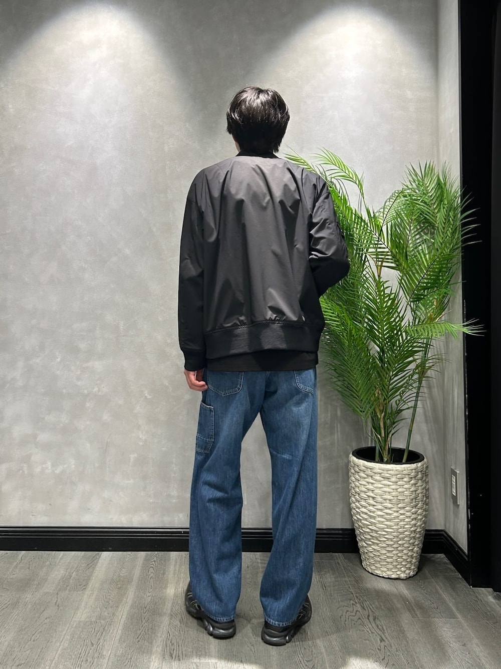 ブラック系のブルゾン、ブラック系のTシャツ/カットソー、ブルー系のデニムパンツを着用したメンズの春コーディネートの3枚目の写真
