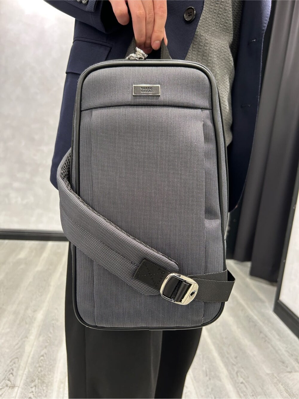 グレー系のニット/セーター、ブルー系のテーラードジャケット、グレー系のショルダーバッグを着用したメンズの秋コーディネートの4枚目の写真