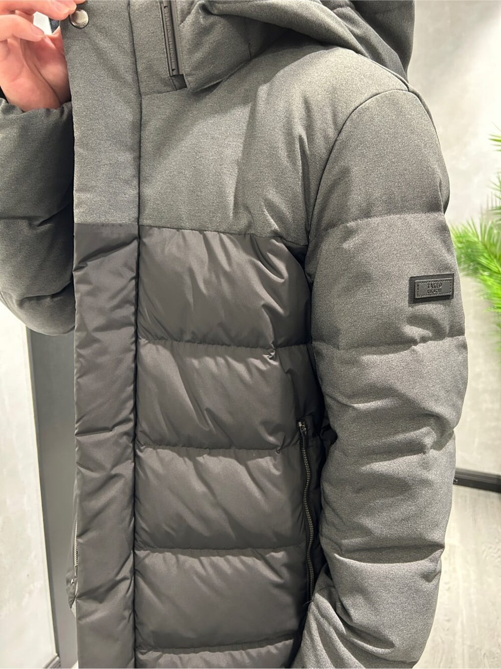 ブラック系のダウンジャケット/コート、グレー系のニット/セーター、ブラック系のスラックスを着用したメンズの冬コーディネートの4枚目の写真