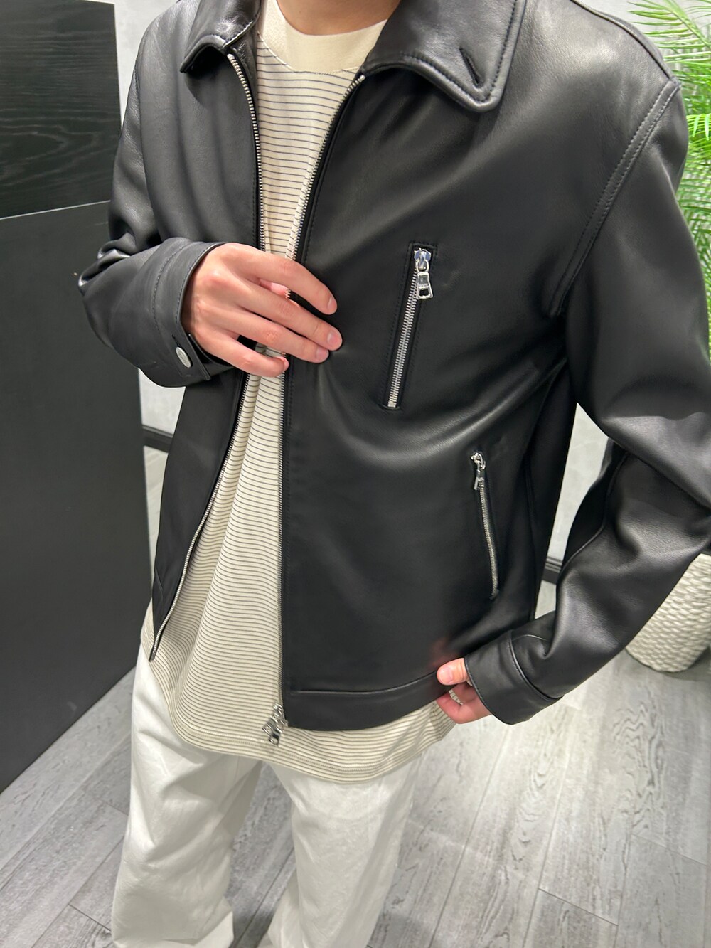 ブラック系のブルゾン、ホワイト系のTシャツ/カットソー、ホワイト系のデニムパンツを着用したメンズの秋コーディネートの3枚目の写真