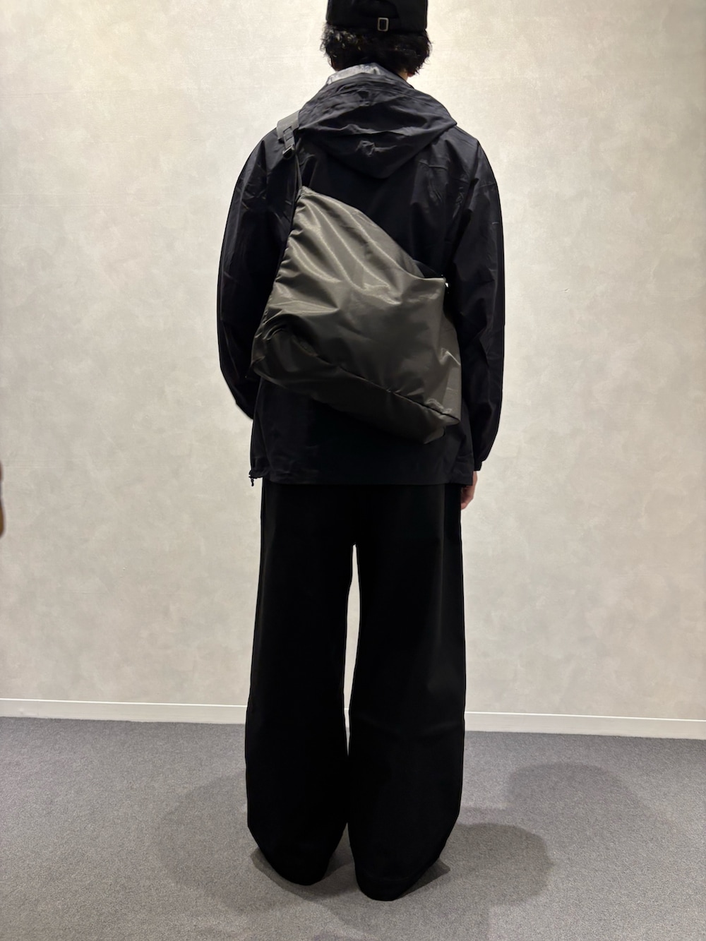 ブラック系のチノパンツ、ブラック系のショルダーバッグ、ブラック系のレインコート/ポンチョを着用したメンズの春コーディネートの2枚目の写真