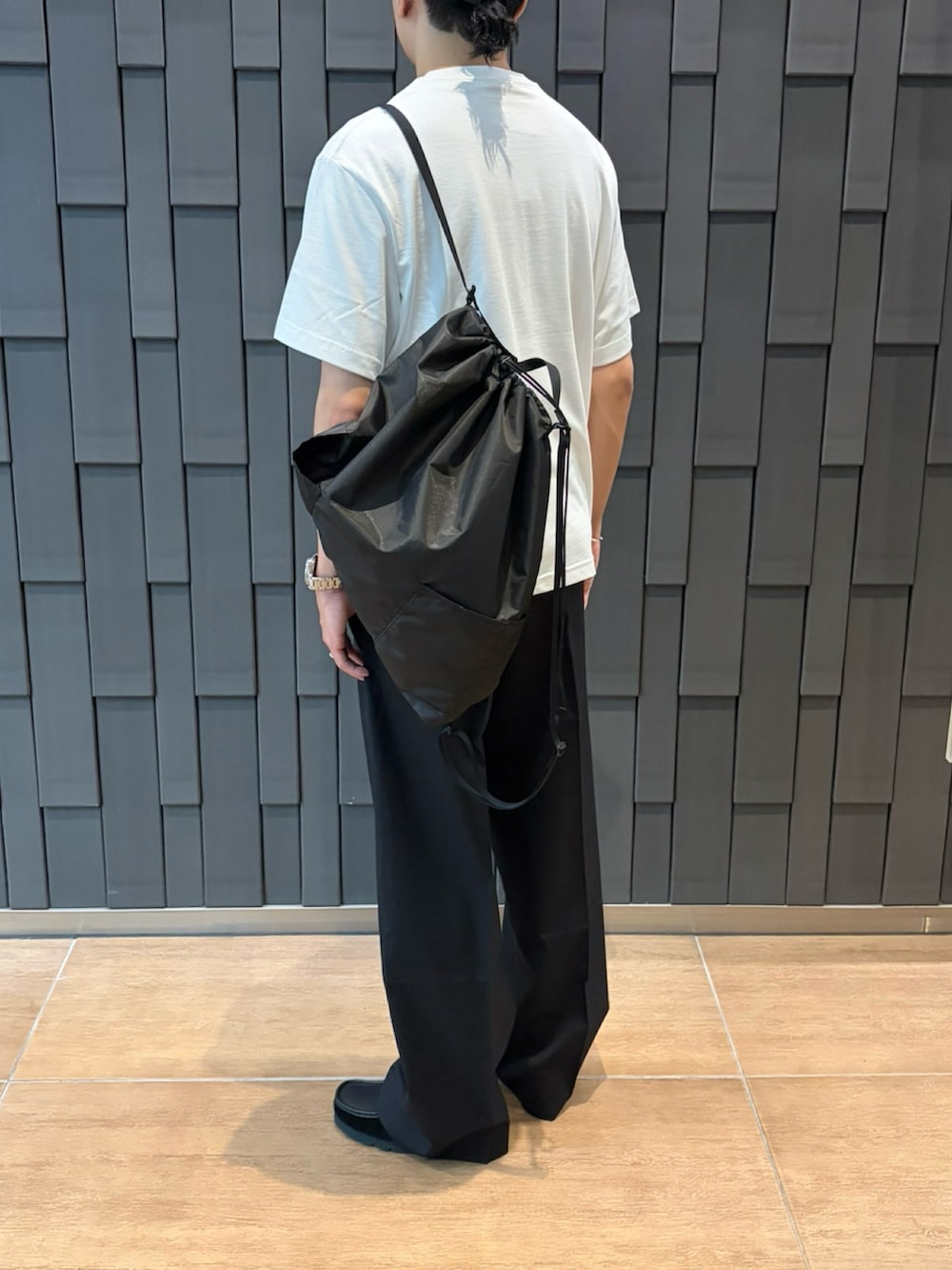 ホワイト系のTシャツ/カットソー、ブラック系のバックパック/リュック、ブラック系のスラックスを着用したメンズの夏コーディネートの2枚目の写真