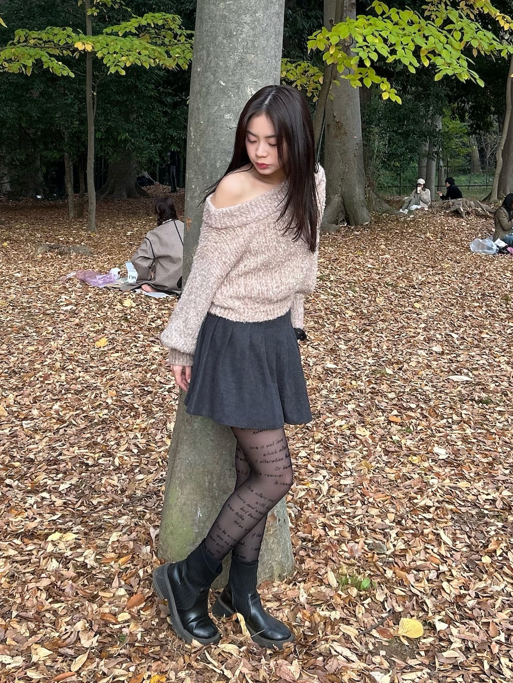 ベージュ系のニット/セーター、グレー系のスカート、ブラック系のブーツを着用したレディースの冬コーディネートの2枚目の写真