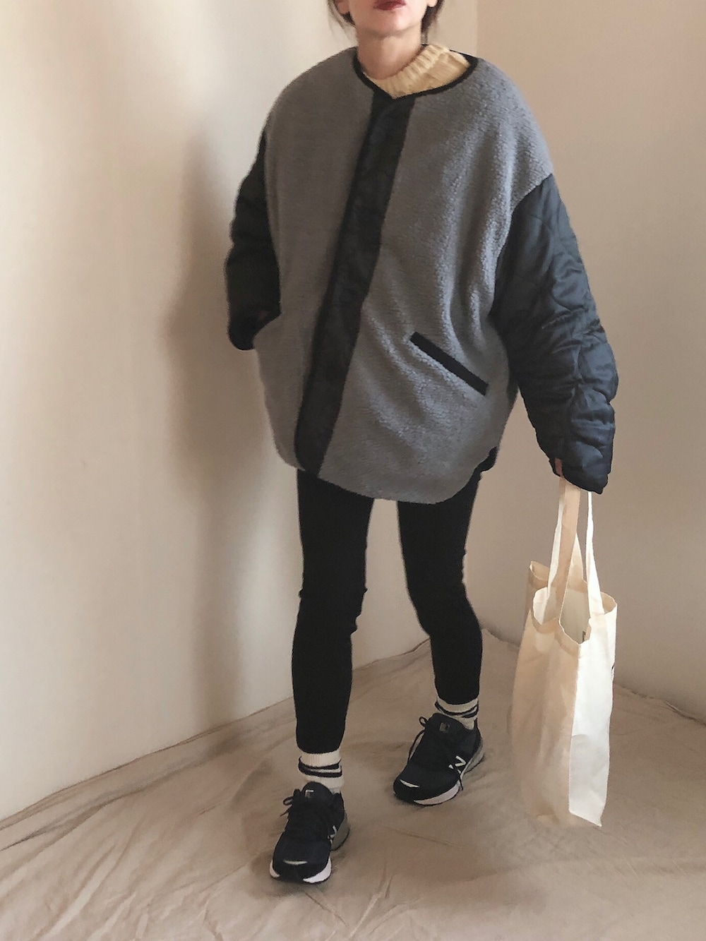 ホワイト系のニット/セーター、グレー系のノーカラージャケット、ブラック系のデニムパンツを着用したレディースの冬コーディネートの2枚目の写真