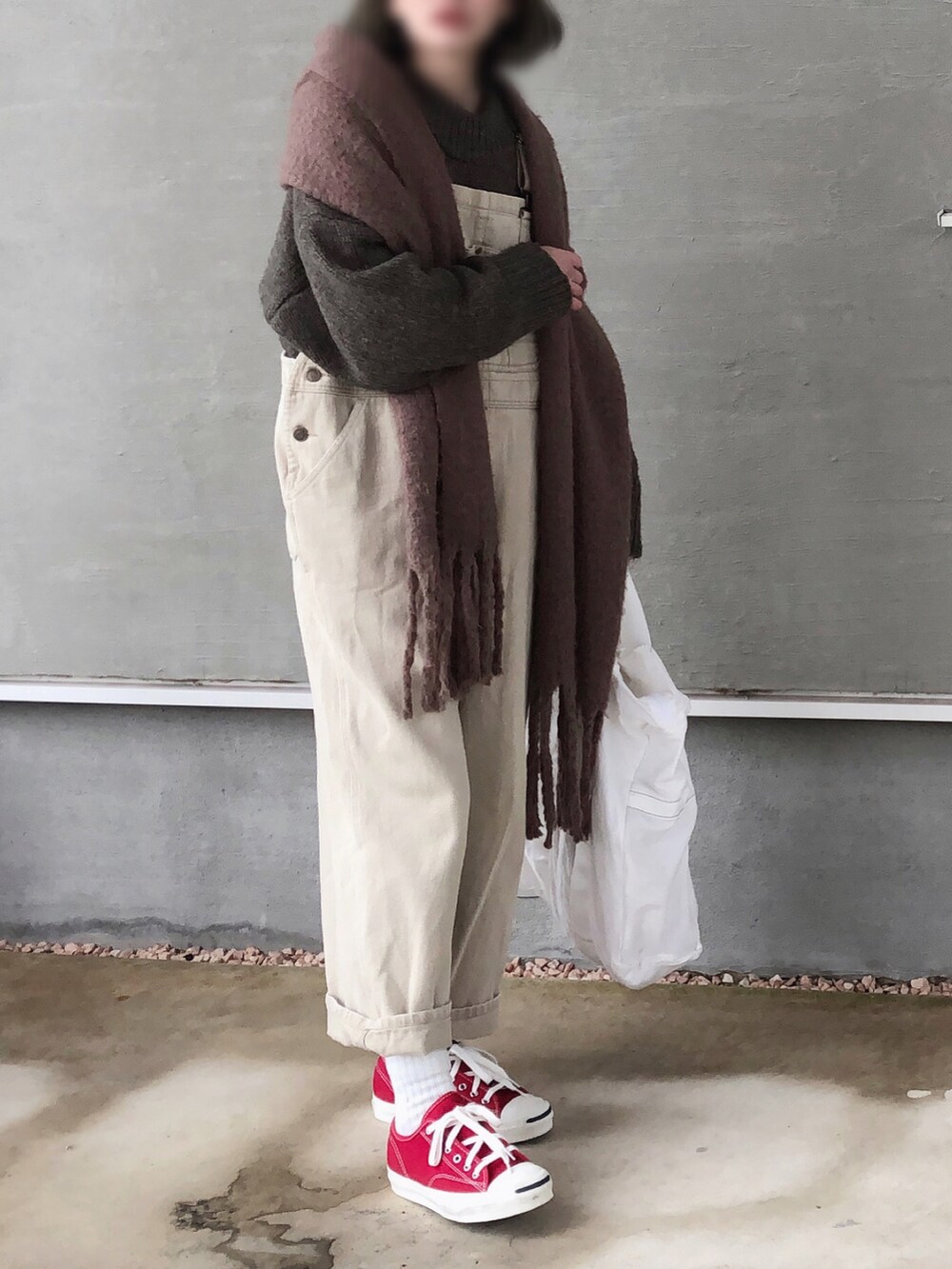 ブラウン系のニット/セーター、ベージュ系のサロペット/オーバーオール、ホワイト系のトートバッグを着用したレディースの冬コーディネートの2枚目の写真