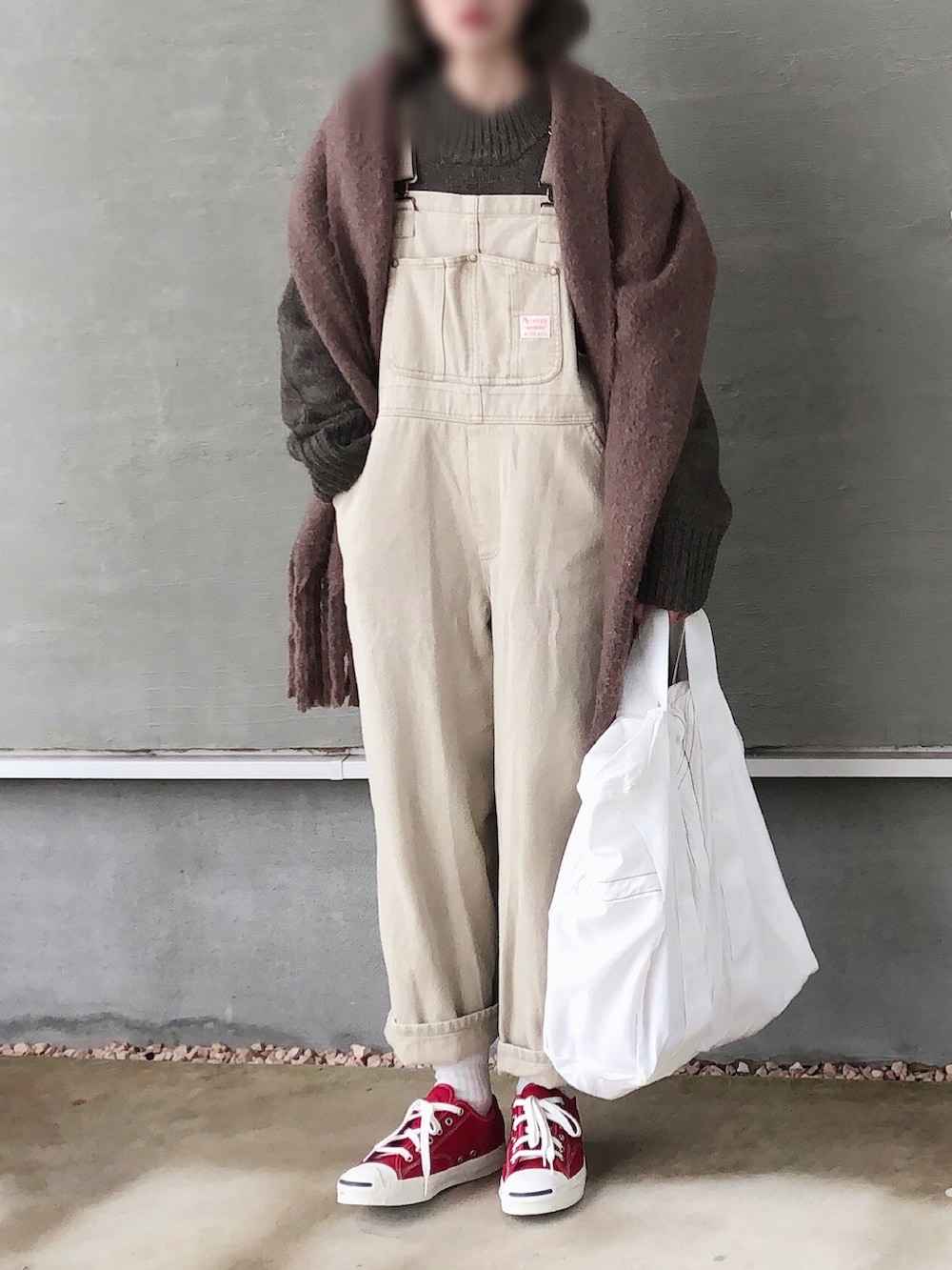 ブラウン系のニット/セーター、ベージュ系のサロペット/オーバーオール、ホワイト系のトートバッグを着用したレディースの冬コーディネートの4枚目の写真