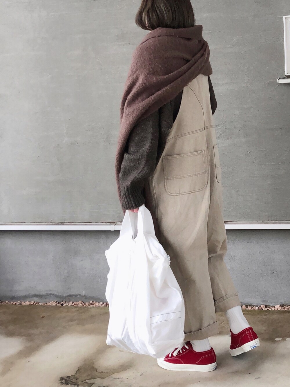 ブラウン系のニット/セーター、ベージュ系のサロペット/オーバーオール、ホワイト系のトートバッグを着用したレディースの冬コーディネートの3枚目の写真