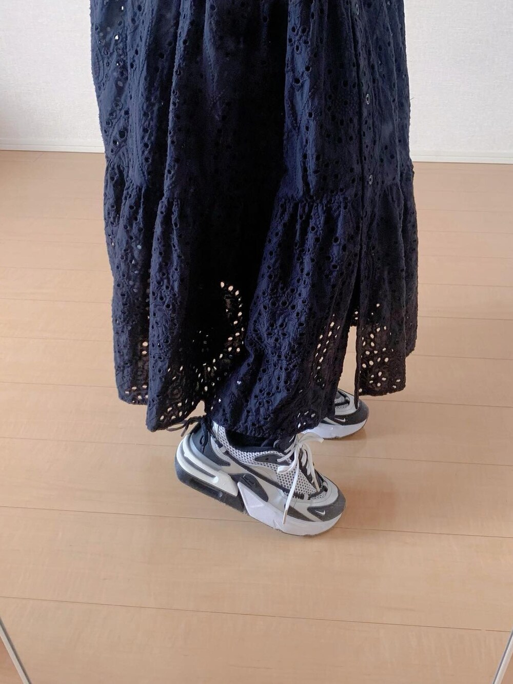 オレンジ系のTシャツ/カットソー、ブラック系のワンピース、ブラック系のスニーカーを着用したレディースの春コーディネートの3枚目の写真