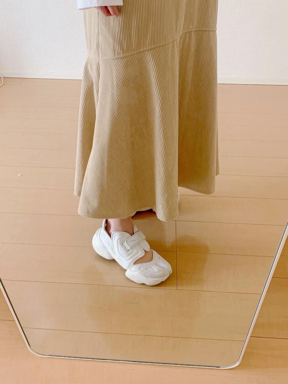 ベージュ系のワンピース、ホワイト系のTシャツ/カットソー、ホワイト系のスニーカーを着用したレディースの春コーディネートの3枚目の写真