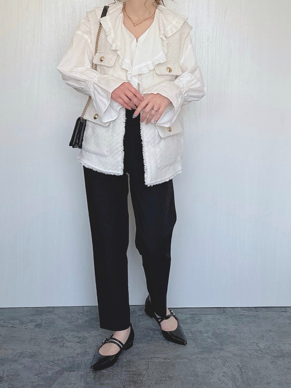 ホワイト系のシャツ/ブラウス、ホワイト系のベスト、ブラック系のパンツを着用したレディースの春コーディネートの2枚目の写真