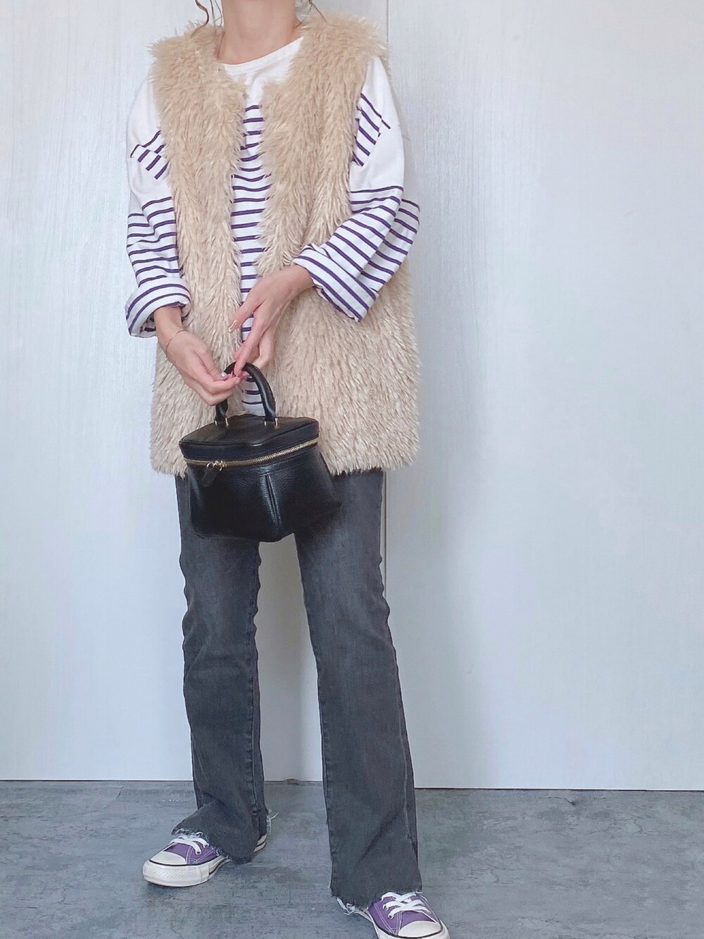 ホワイト系のベスト、ブラック系のデニムパンツを着用したレディースの秋コーディネートの2枚目の写真