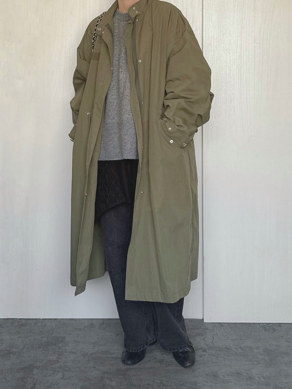 グリーン系のモッズコート、グレー系のニット/セーター、ブラック系のデニムパンツを着用したレディースの冬コーディネートの2枚目の写真