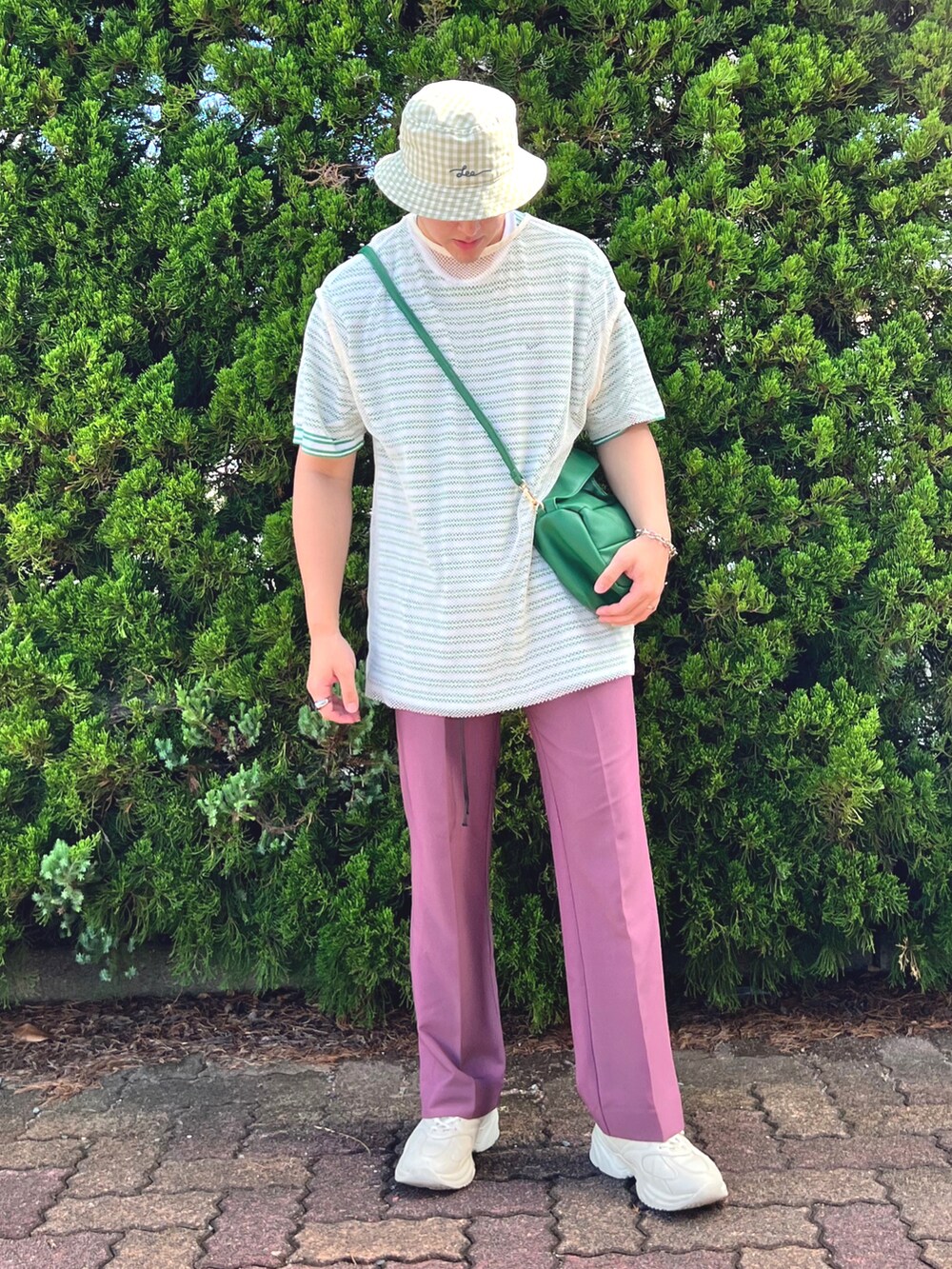 グリーン系のバッグ、グリーン系のTシャツ/カットソー、パープル系のスラックスを着用したメンズの夏コーディネートの2枚目の写真